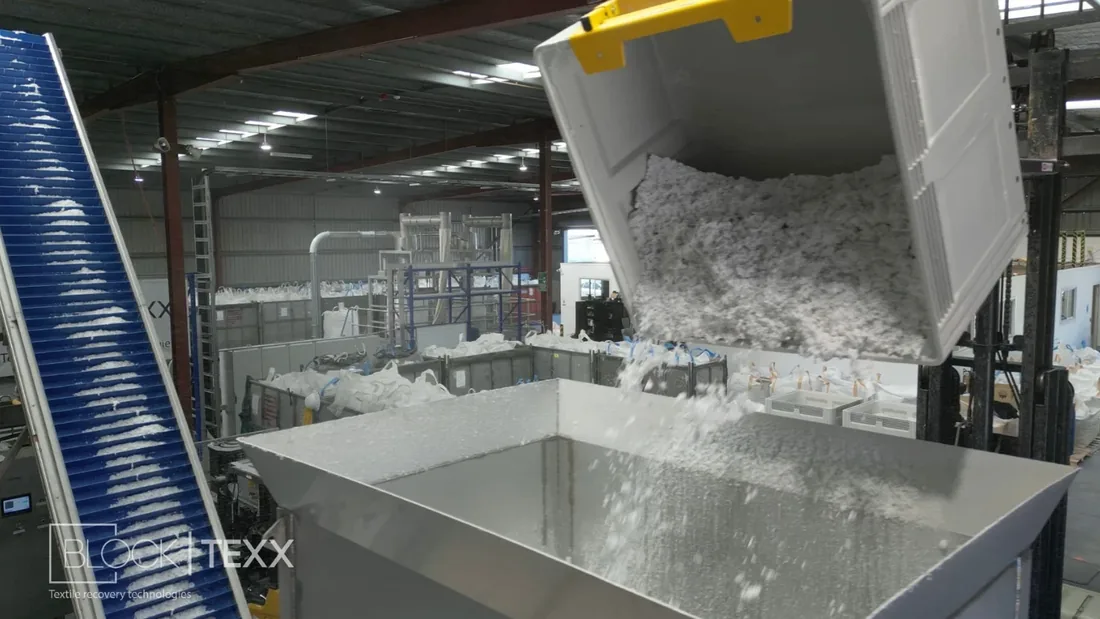 Shredded textile material tipped into a hopper inside the BlockTexx facility