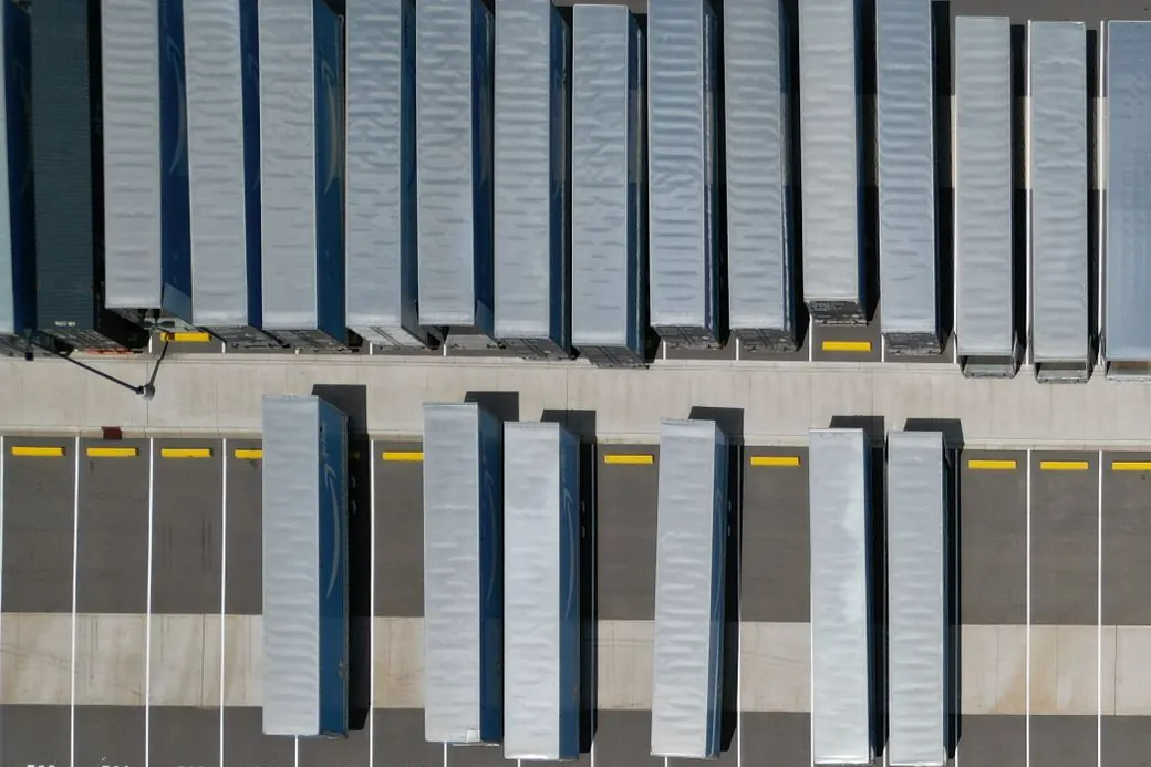 Trailers parked in marked bays on a large sealed hardstand, seen from above